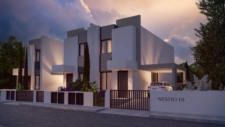 The Nestio 19 gate wall at dusk with the homes lit behind it